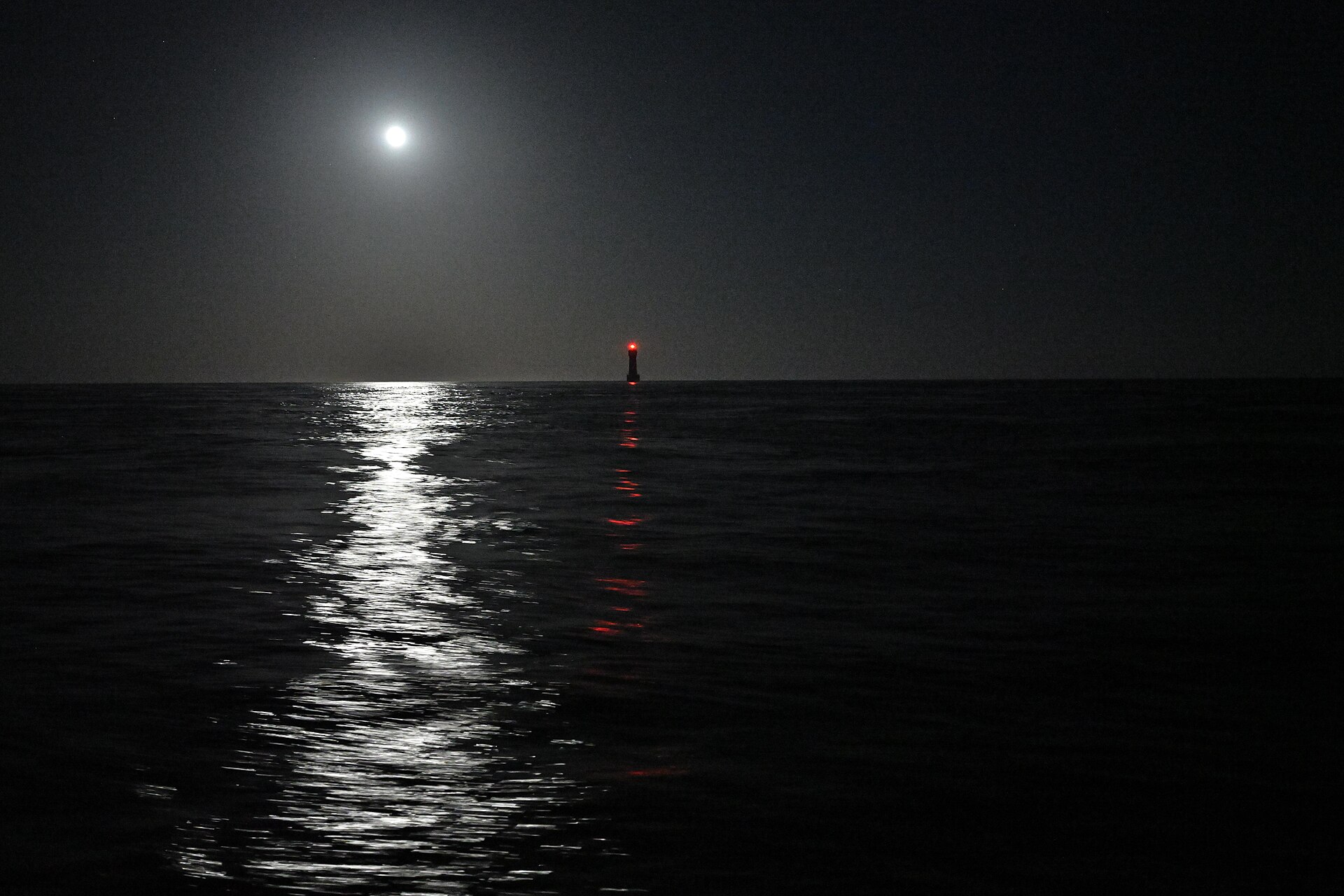 Nuit de pleine lune sur la mer, feu du phare de la Jument au loin